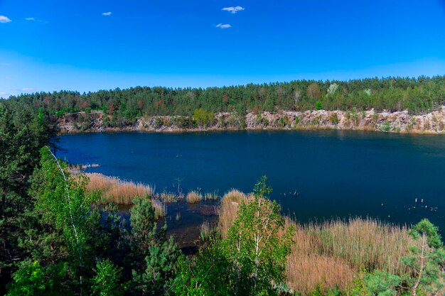 Hermosa vista de la cantera de granito inundada. Costas de rocas graníticas y bosque alrededor de la cantera. Foto panorámica del paisaje.