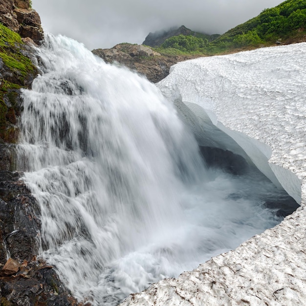 Hermosa vista de la cascada que cae en el glaciar en la montaña rocosa