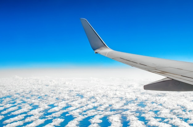 Hermosa vista clásica del ojo de buey durante un vuelo en avión, nubes de cielo azul y tierra.