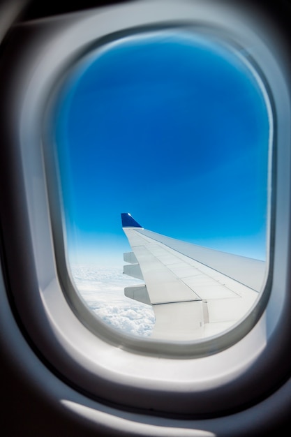 Hermosa vista de Cloudscape y ala de avión vista a través de la ventana de un avión