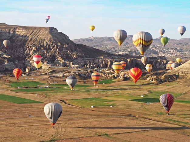 Hermosa vista de los globos coloridos del aire caliente que vuelan sobre paisaje en cappadocia, turquía.