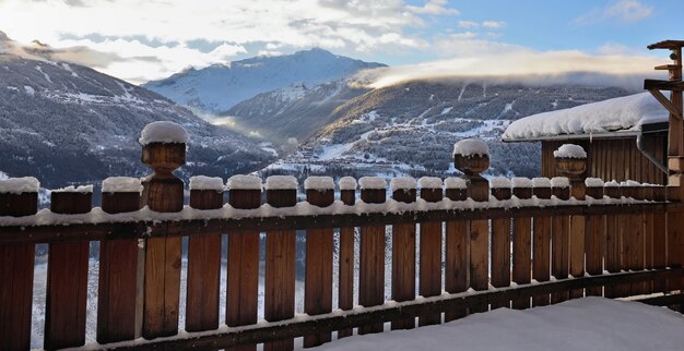 Hermosa vista de invierno en la montaña alpina desde una terraza de madera con valla y cubiertos con la nieve.