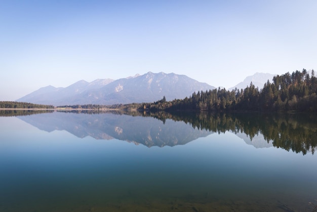 Hermosa vista de un lago con el reflejo de árboles y montañas en la A