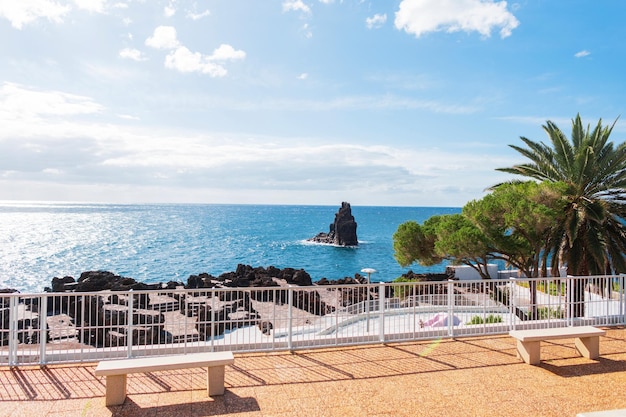 Hermosa vista del océano azul con el cielo en el paseo marítimo con bancos y palmeras Vacaciones en la isla de Madeira Océano Atlántico