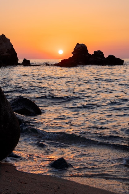 Foto hermosa vista del paisaje marino naranja al atardecer con rocas en italia paisaje colorido amanecer