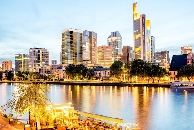 Hermosa vista del paisaje urbano sobre los rascacielos iluminados y el puente durante el crepúsculo en Frankfurt, Alemania