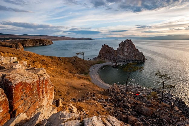 Hermosa vista de la roca sagrada de Shamanka en la isla de Olkhon al atardecer Hay nubes claras en el cielo Luz en las piedras Montañas en el horizonte