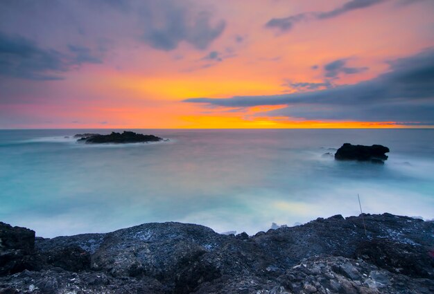 Hermosa vista con rocas y colinas durante la increíble puesta de sol en la playa de Menganti, Java central