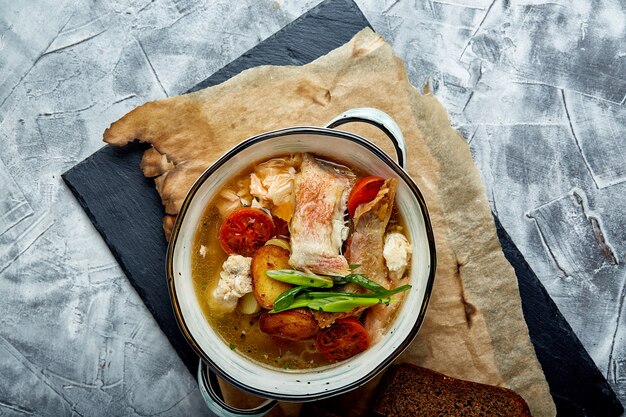 Hermosa vista de sopa de pescado en un plato blanco, sobre un fondo de piedra