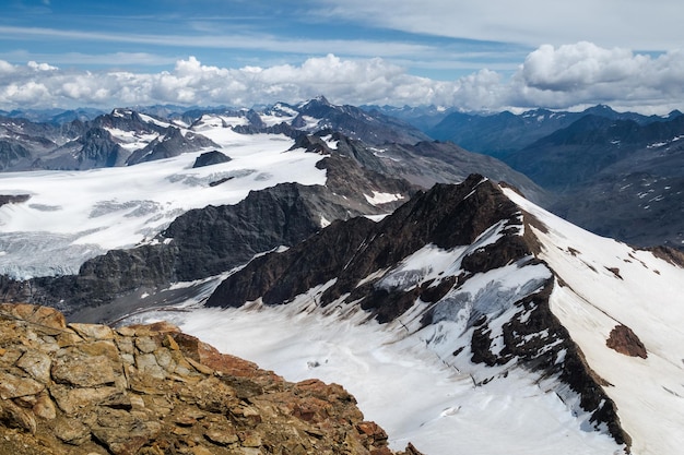 Hermosa vista de Weisskugel en la frontera italo-austríaca con nubes bajas sobre picos nevados