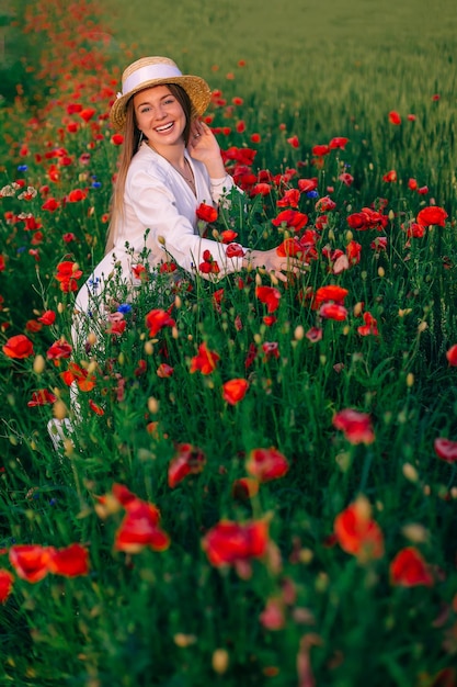 Hermosas amapolas rojas y una chica con vestido blanco y navegante miran