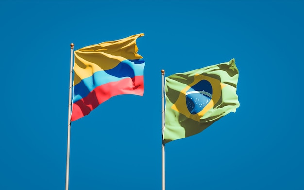 Hermosas banderas del estado nacional de Brasil y Colombia juntos en el cielo azul