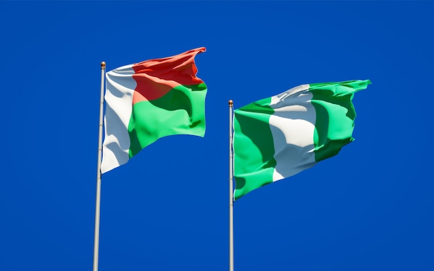 Hermosas banderas del estado nacional de Madagascar y Nigeria juntos en el cielo azul