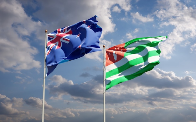 Hermosas banderas del estado nacional de Nueva Zelanda y Abjasia juntos en el cielo azul. Ilustraciones 3D