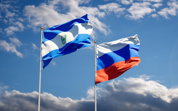 Hermosas banderas del estado nacional de Rusia y El Salvador juntos en el cielo azul. Ilustraciones 3D