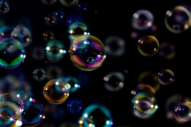Hermosas burbujas de jabón de colores brillantes flotando en la oscuridad. Fondo de verano fresco abstracto, Natual.