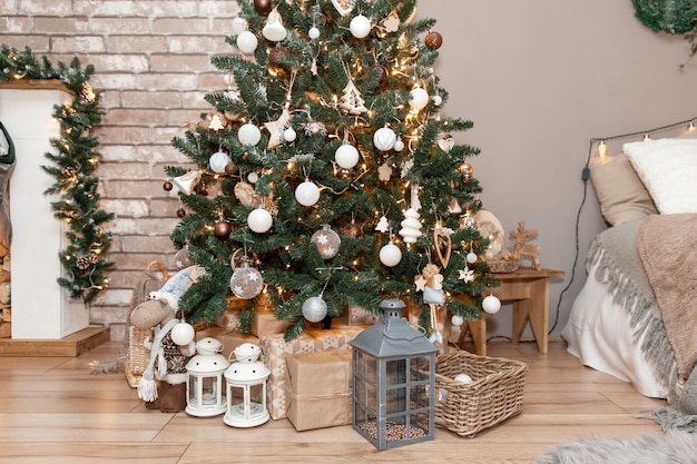 Hermosas cajas de regalo de Navidad en el piso cerca de abeto en la habitación