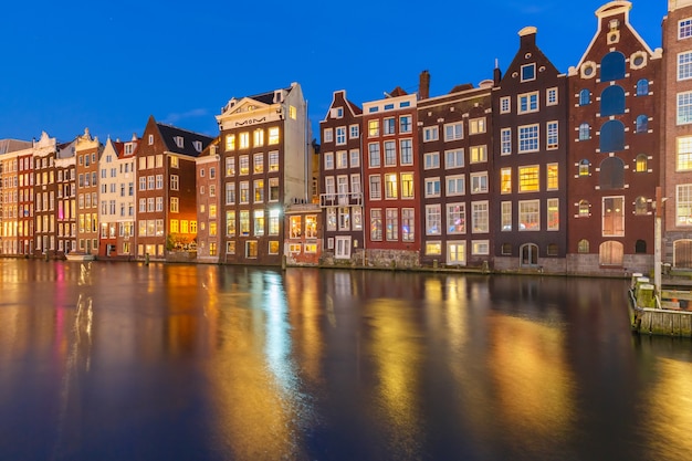 Hermosas casas de baile típico holandés en el canal Damrak de Amsterdam en la noche, Holanda, Países Bajos.