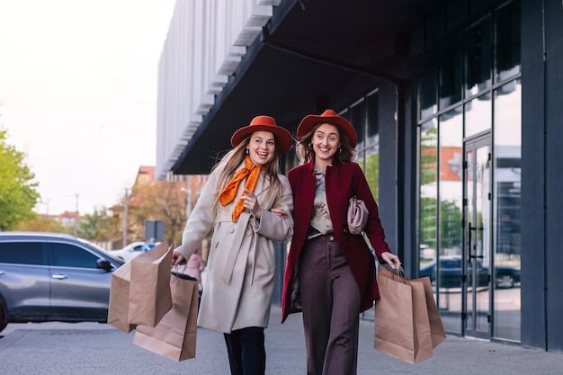 Hermosas chicas con bolsas de compras caminando en el centro comercial