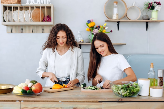 Hermosas chicas cocinando comida deliciosa y saludable en la cocina