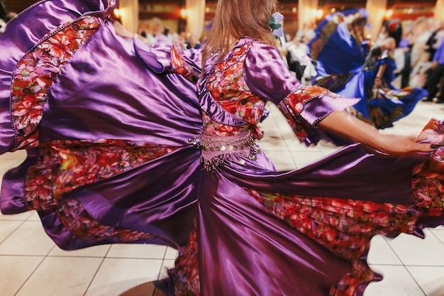 Hermosas chicas gitanas bailando con el tradicional vestido floral púrpura en la recepción de la boda en el restaurante mujer interpretando danza romaní y canciones folclóricas en ropa nacional festival gitano de roma