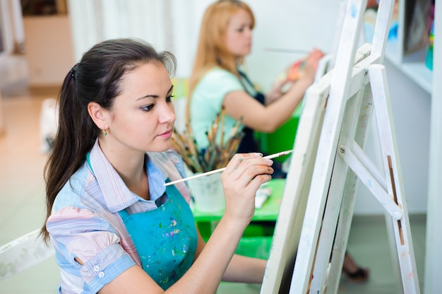 Hermosas chicas jóvenes dibujan pinturas en una clase de arte