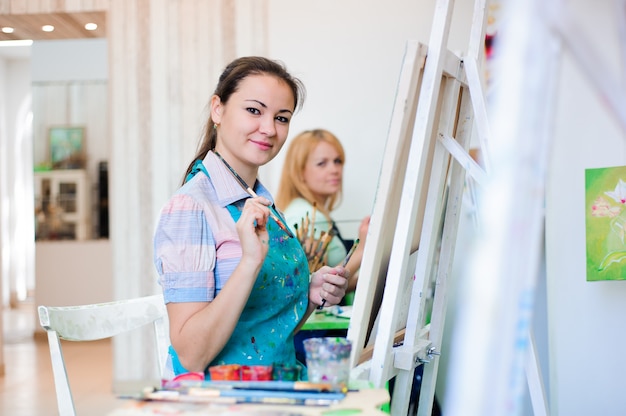 Hermosas chicas jóvenes dibujan pinturas en una lección de arte