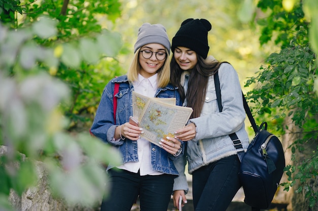 hermosas chicas jóvenes y elegantes caminando por el parque y buscando una dirección