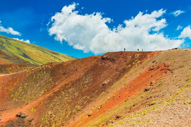 Hermosas colinas de lava coloridas con un grupo de personas caminando hacia un cráter volcánico. Monte Etna, Sicilia, Italia