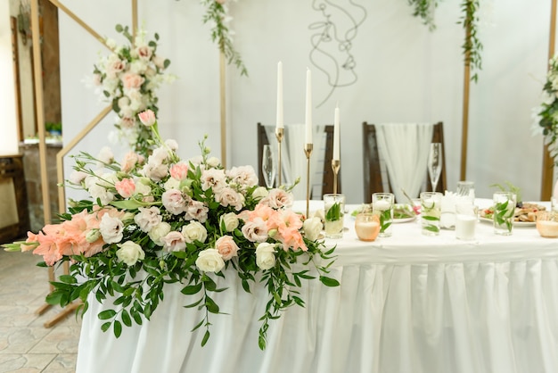 Hermosas composiciones florales en el restaurante para la ceremonia de la boda. Ceremonia solemne de pintar al novio y a la novia
