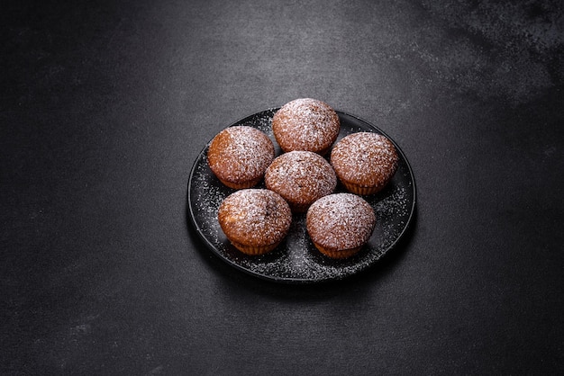 Hermosas y deliciosas magdalenas con cacao y pasas sobre un fondo de hormigón negro Hora de beber té