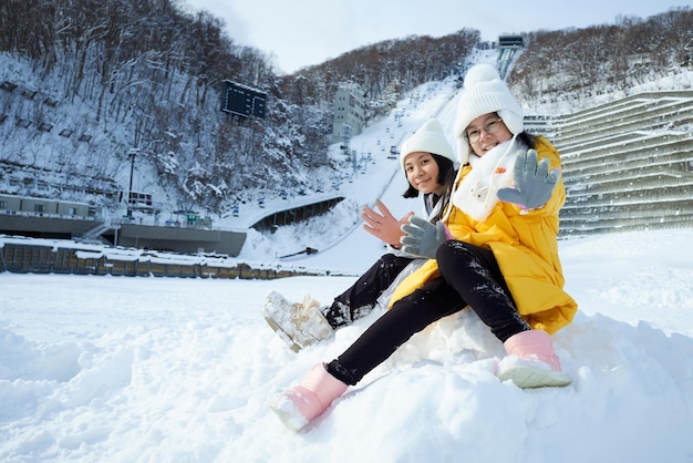 Hermosas dos hermanas asiáticas sonriendo felices con los viajes en la temporada de invierno con nieve en Hokkaido