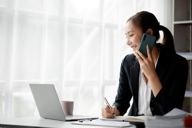 Hermosas ejecutivas asiáticas ejecutivas de negocios ejecutivos de marketing están hablando por teléfono con clientes para contactar a la empresa para marketing Concepto de gestión de marketing