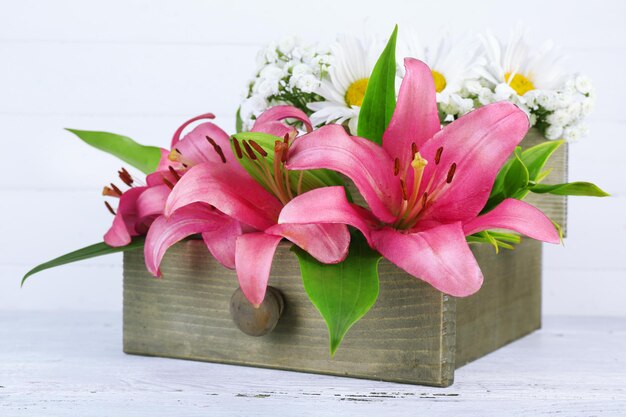 Hermosas flores en caja sobre fondo de madera