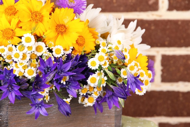 Hermosas flores en caja sobre fondo de pared de ladrillo