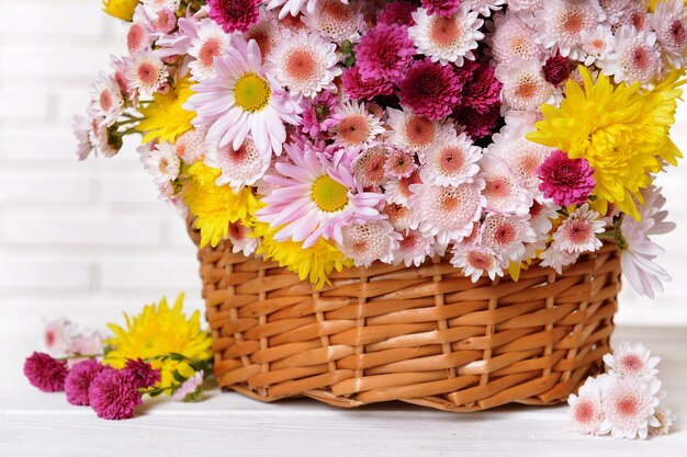 Hermosas flores en una canasta de mimbre en la mesa sobre un fondo claro