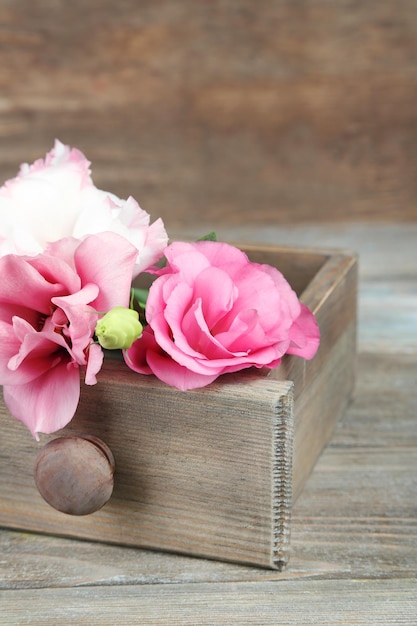 Hermosas flores de eustoma en caja sobre fondo de madera