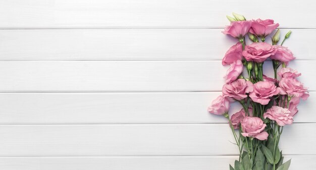 Hermosas flores de eustoma rosa sobre fondo blanco de madera. Copie el espacio, vista superior