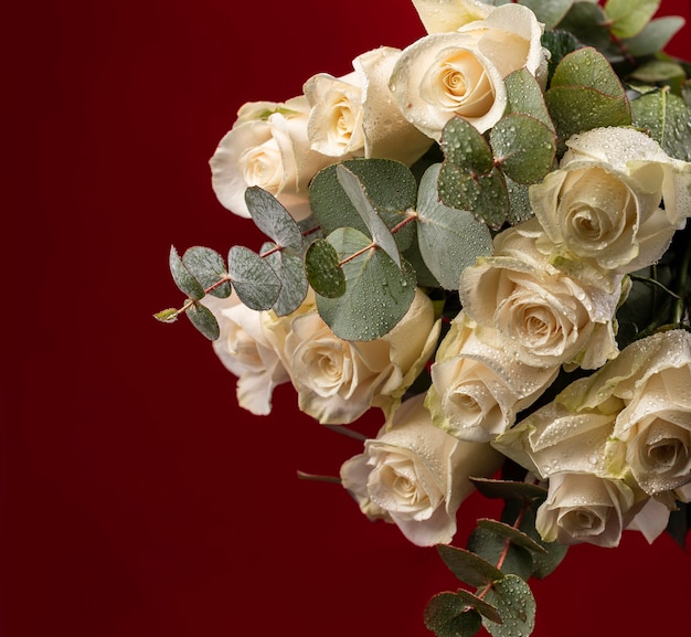 Hermosas flores frescas con gotas de agua y ramas del árbol de eucalipto