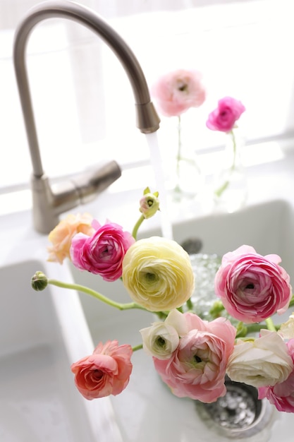 Hermosas flores frescas de ranunculus en el fregadero de la cocina