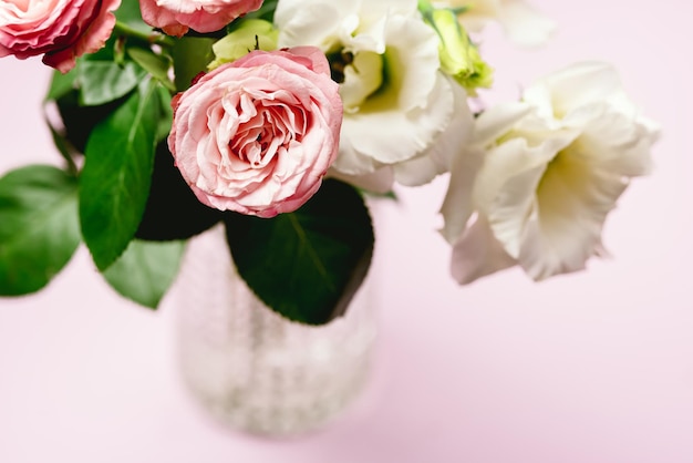 Hermosas flores en un jarrón Fondo de primavera Flores blancas y rosadas sobre fondo rosa Espacio de copia Rosas rosas horizontales y Eustoma Tarjeta navideña