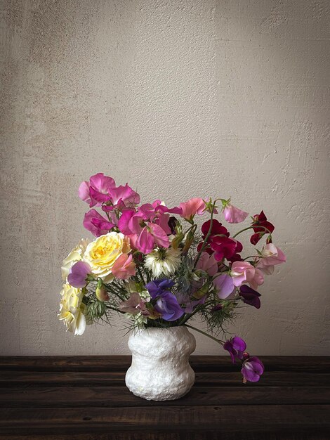 Hermosas flores en un jarrón sobre un fondo rústico de mal humor Flores con estilo bodegón composición artística de lathyrus amor en la niebla rosa Papel tapiz floral vertical