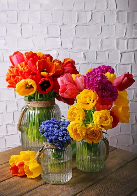 Hermosas flores en jarrones sobre fondo de pared