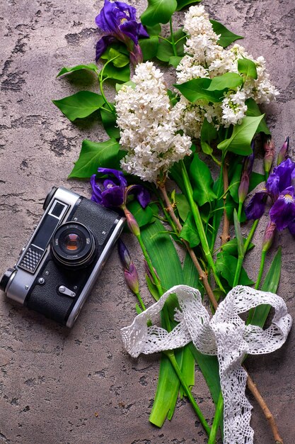 Hermosas flores lilas y cámara antigua sobre fondo de hormigón gris.
