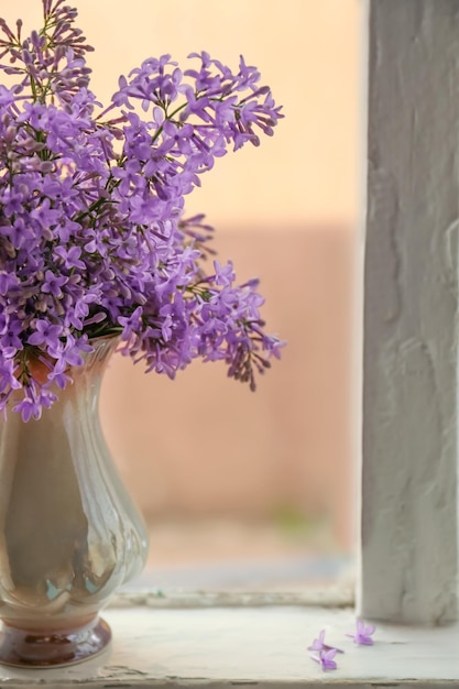 Hermosas flores lilas en jarrón en el alféizar de la ventana en el interior