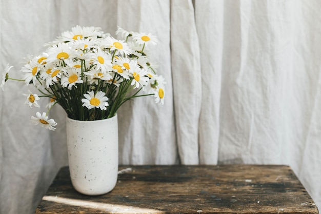 Hermosas flores de margarita en una silla rural de madera en una habitación rústica Vibraciones de verano decoración casera sencilla en el campo Ramo de margaritas en un jarrón de cerámica moderno en una habitación soleada Espacio para copiar