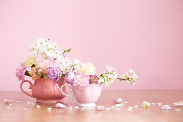 Hermosas flores de primavera en dos tazas vintage sobre fondo rosa