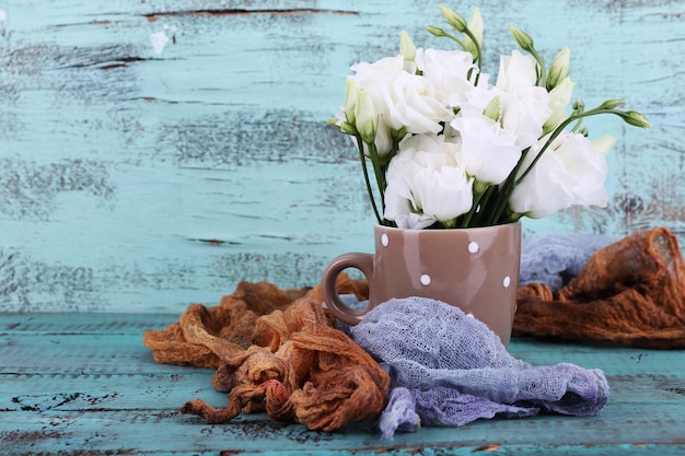 Hermosas flores en taza sobre fondo de madera