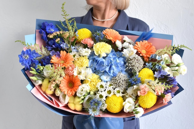 Hermosas flores para vacaciones Mujer con hermosas flores en las manos en el interior de fondo ramo de flores para floristería