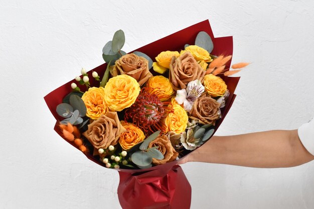 Hermosas flores para vacaciones Mujer con hermosas flores en las manos en el interior de fondo ramo de flores para floristería